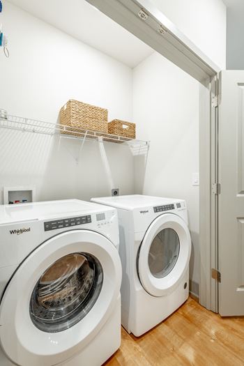 A front load washer and dryer in a laundry room with shelving